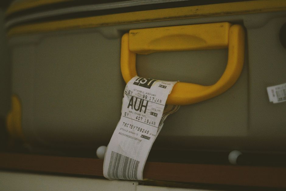 Close-up of a yellow suitcase handle with a visible travel tag and barcode, ideal for travel themes.